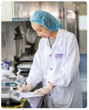 A person in protective lab gear making a note.