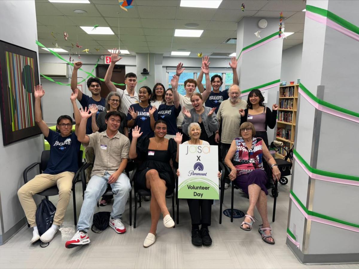 Paramount interns and an elderly woman holding a "Volunteer Day" sign