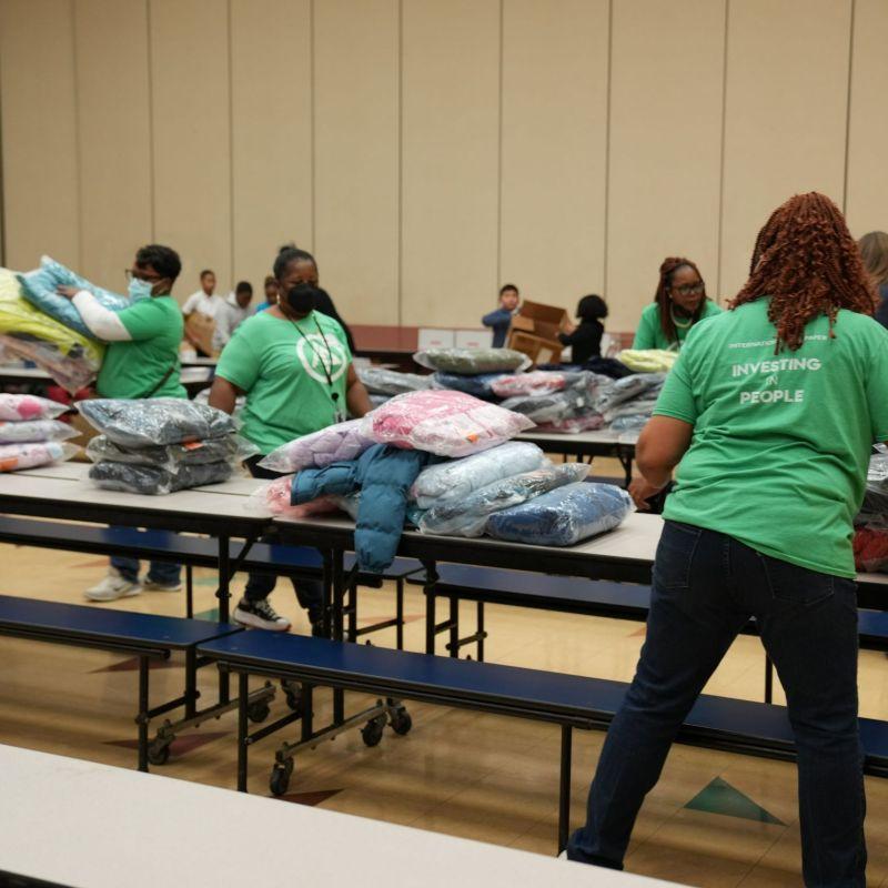 International Paper volunteers place coats on school cafeteria tables