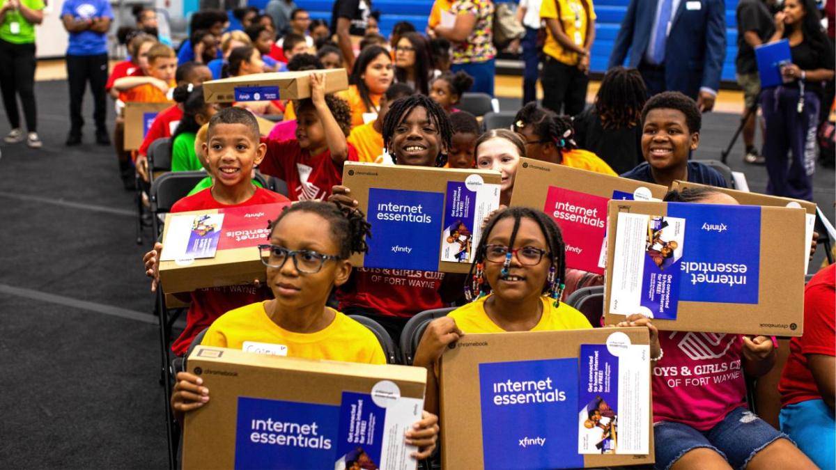 Children seated in a group, each holding a new laptop.