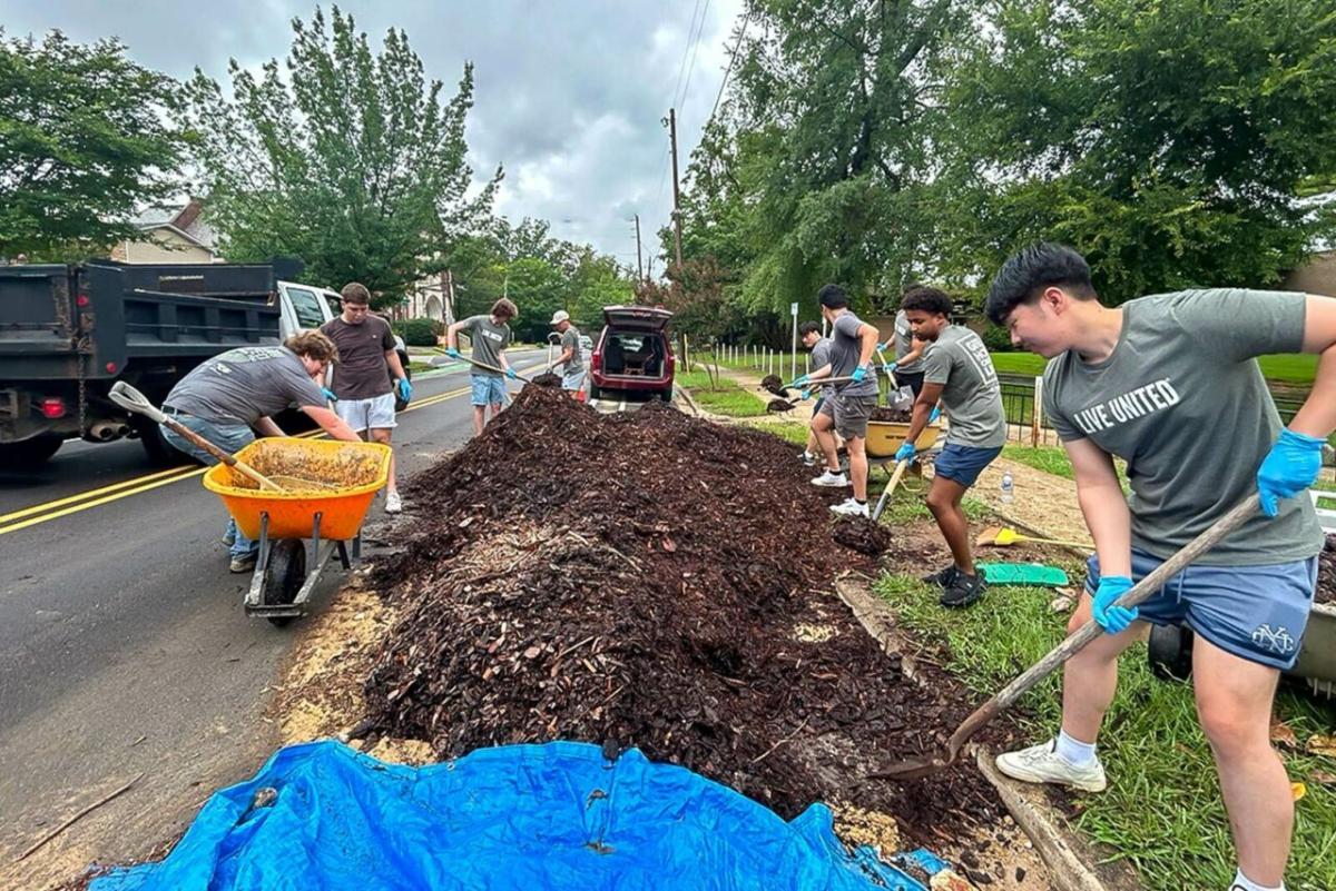 Volunteers shoveling mulch.