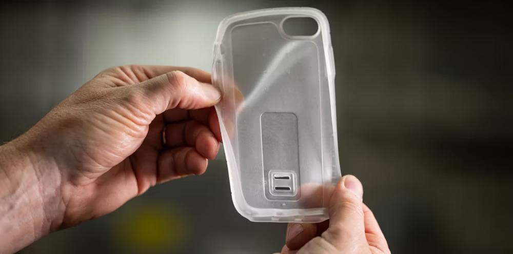 Two hands holding a clear, flexible, plastic device cover.