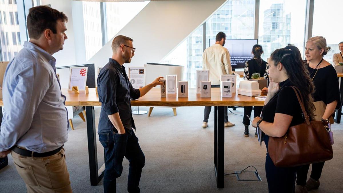 A person explaining to others, pointing to boxes for products.