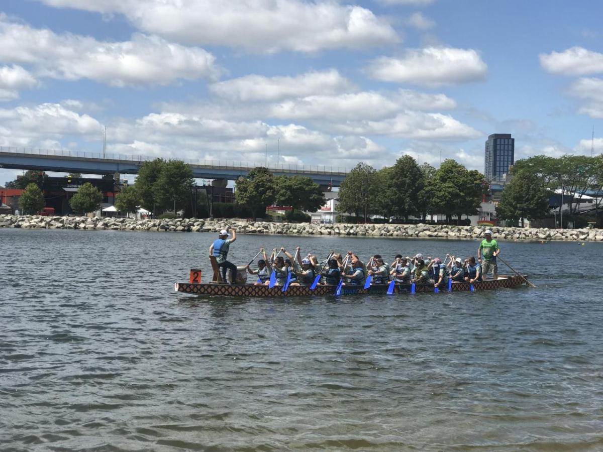 A group in a long boat paddling on a body of water.