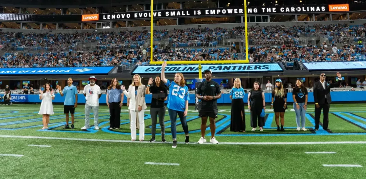 A line of people waving on a football field.