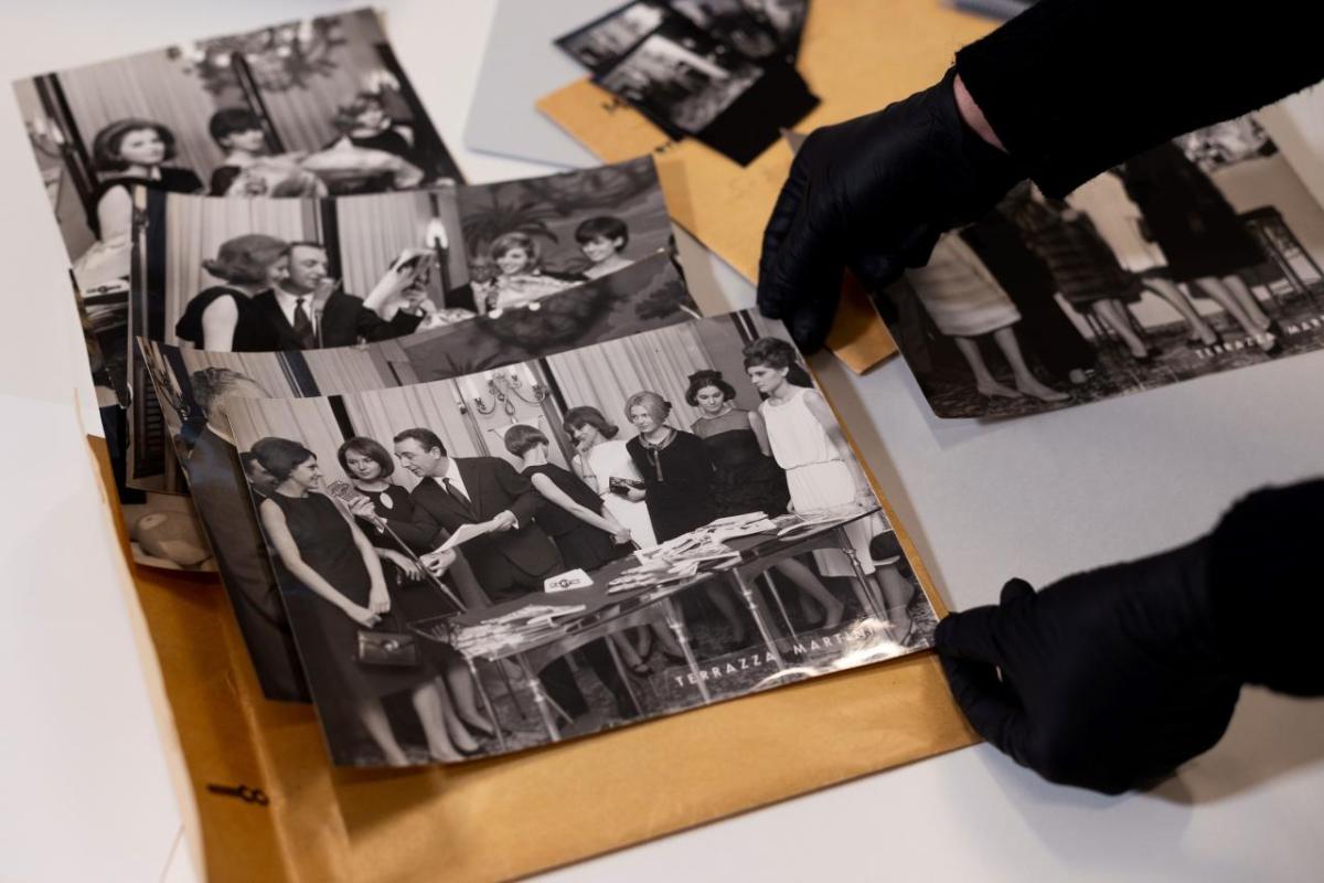 Gloved hands holding a black and white photo.