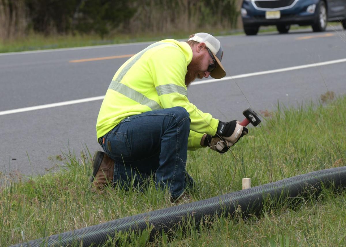 Volunteer working with a drain pipe on the side of a road.
