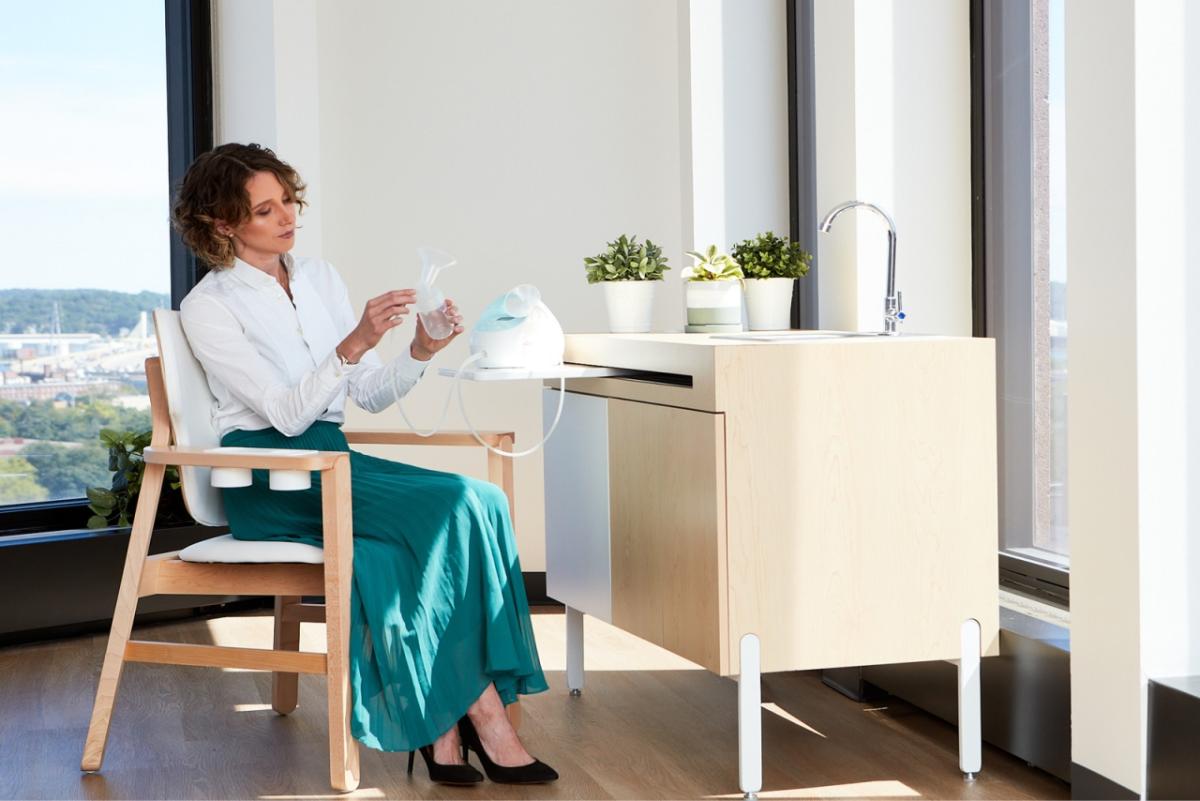 A person sitting in a specialized chair looking at a breast pump