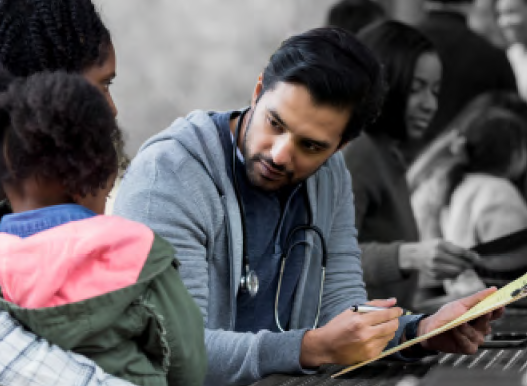 a doctor sits writing on a clipboard, an adult and child on the left