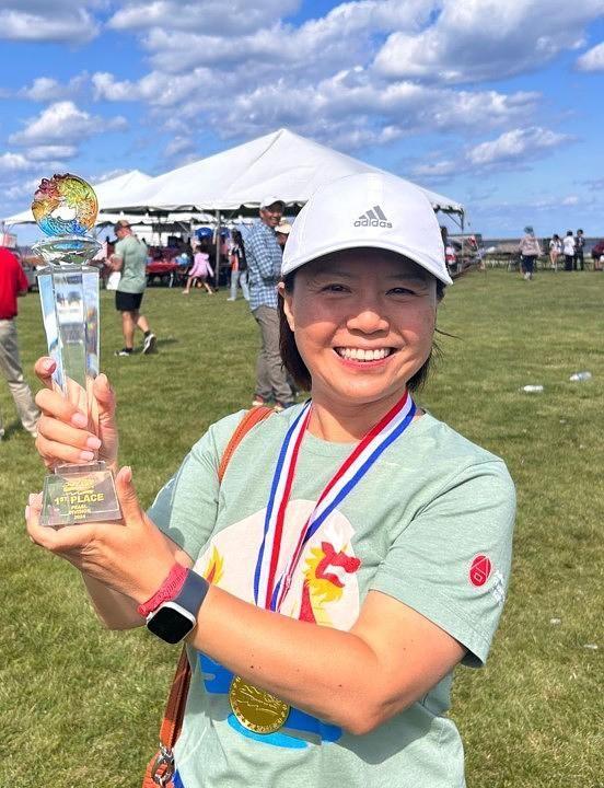 A smiling person holding an award outside.