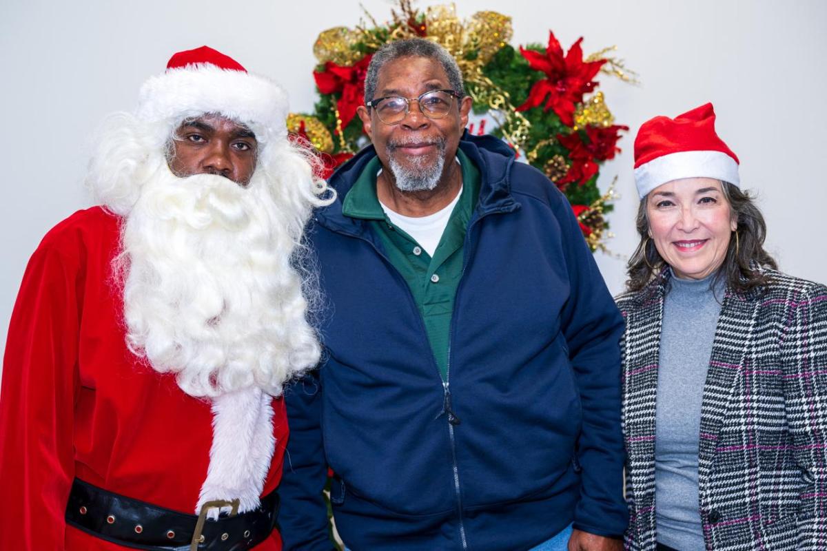 A recipient posed with Santa and Entergy employees.