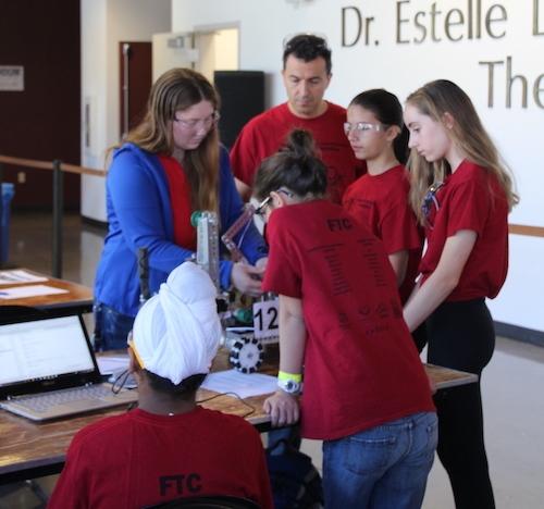 A group of youth and adults working on a robot.