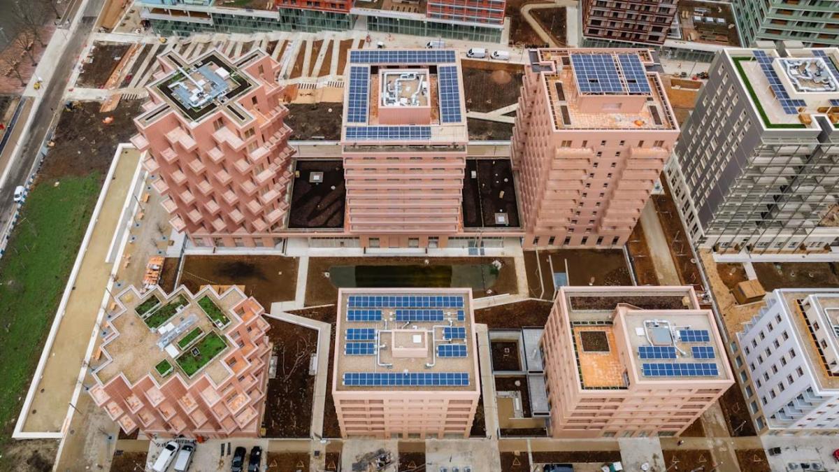 Aerial view of rows of tall buildings, most with solar panels on the roofs.