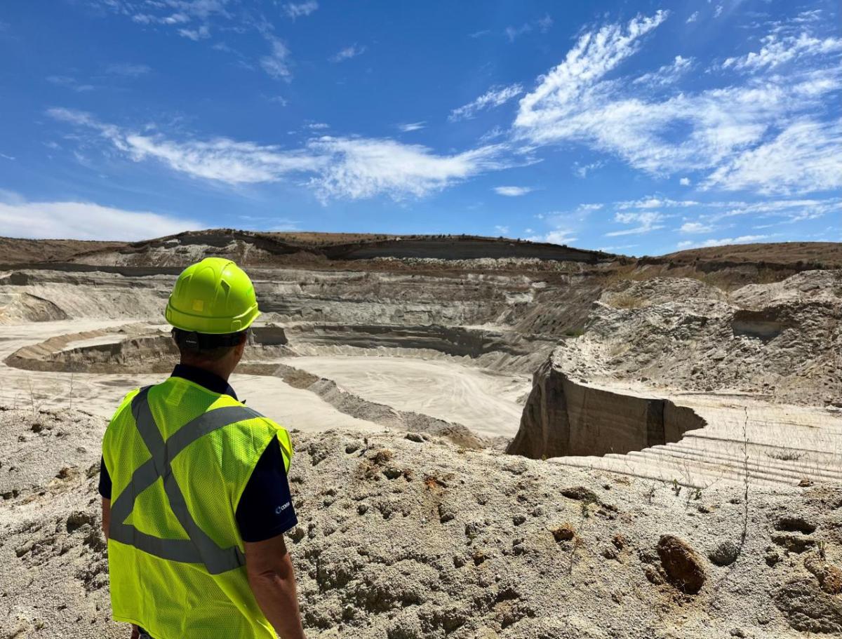 A person in a hard hat and high-vis vest looking out over a quarry area.