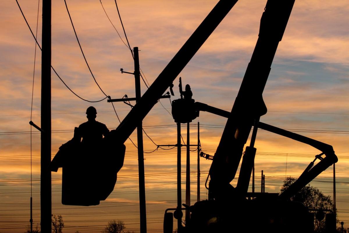 silhouette of someone working on a powerline