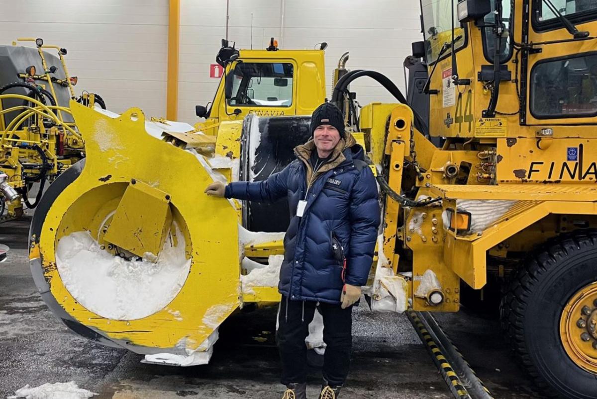A person standing next to a large snow plow.