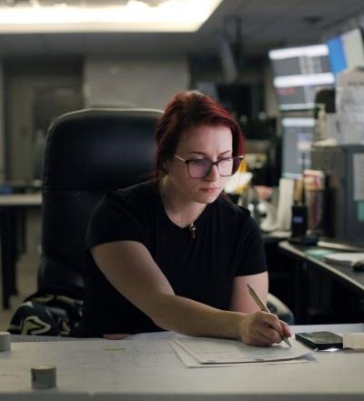 An employee writing on a piece of paper in an office setting.