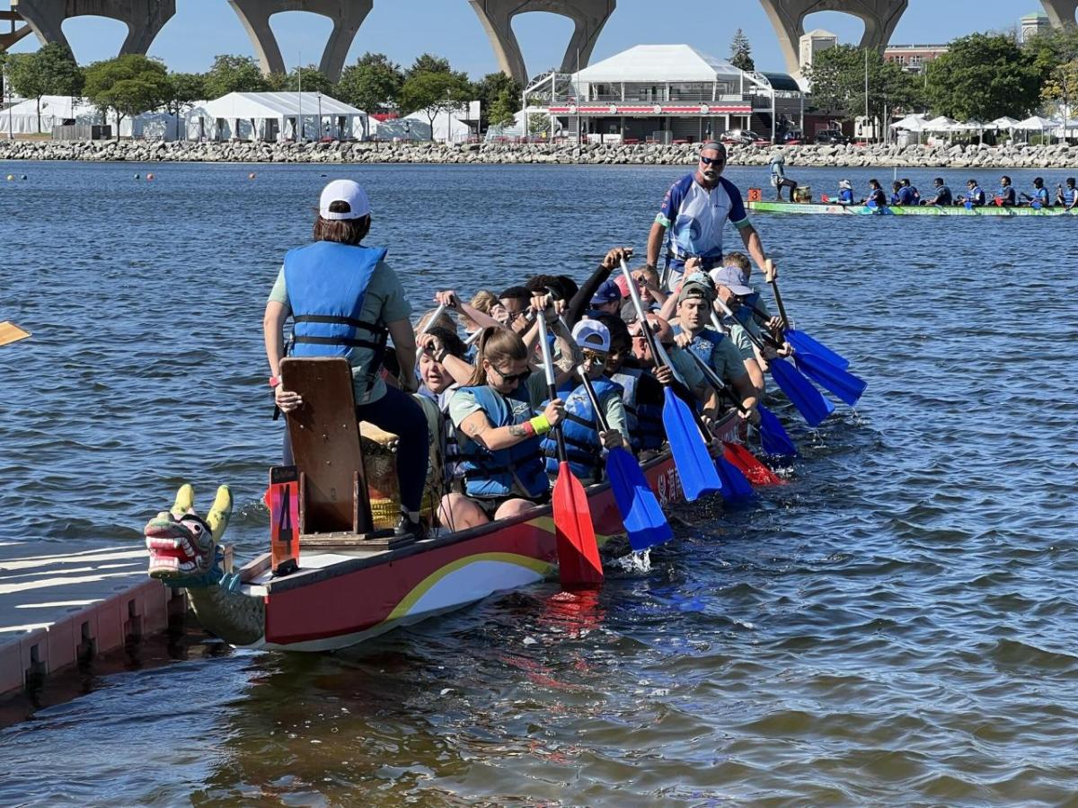 A group in a long boat paddling on a body of water.