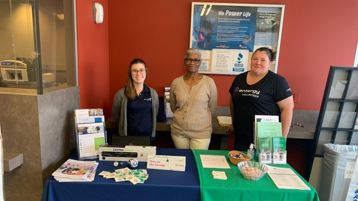 Three people standing behind a display table.