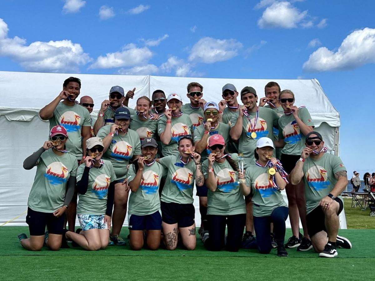 A group posed, each biting a medal.