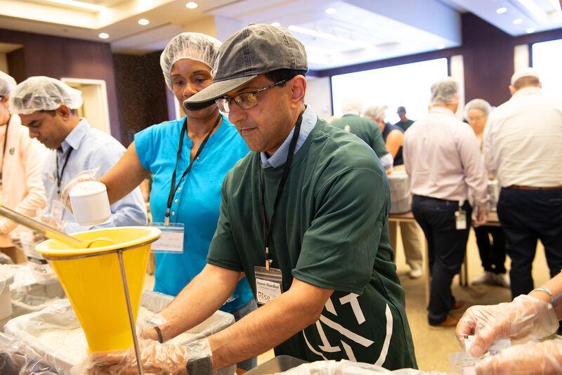 Volunteers in assembly lines packing food.