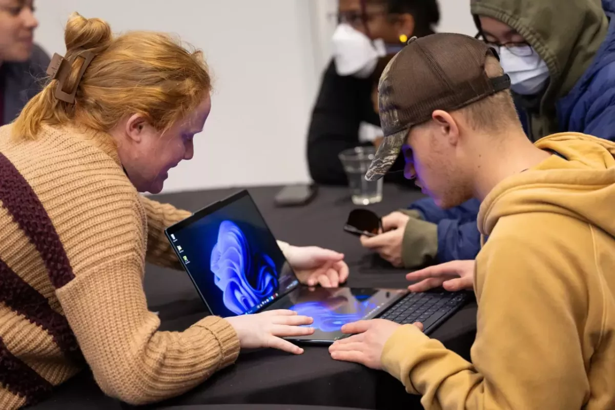 Two people working with an open laptop.