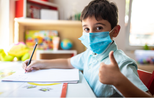 Young student wearing mask giving thumbs up