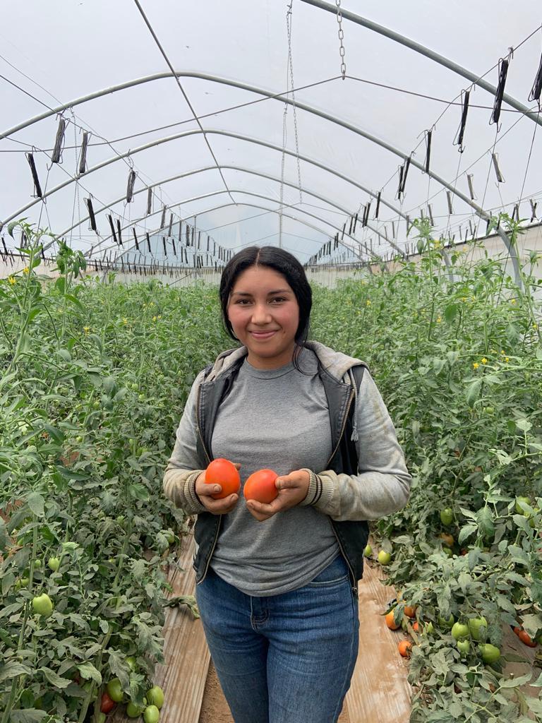 Gloribel holding two tomatoes