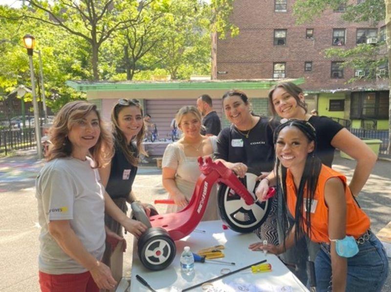 a group of people outside working on a tricycle