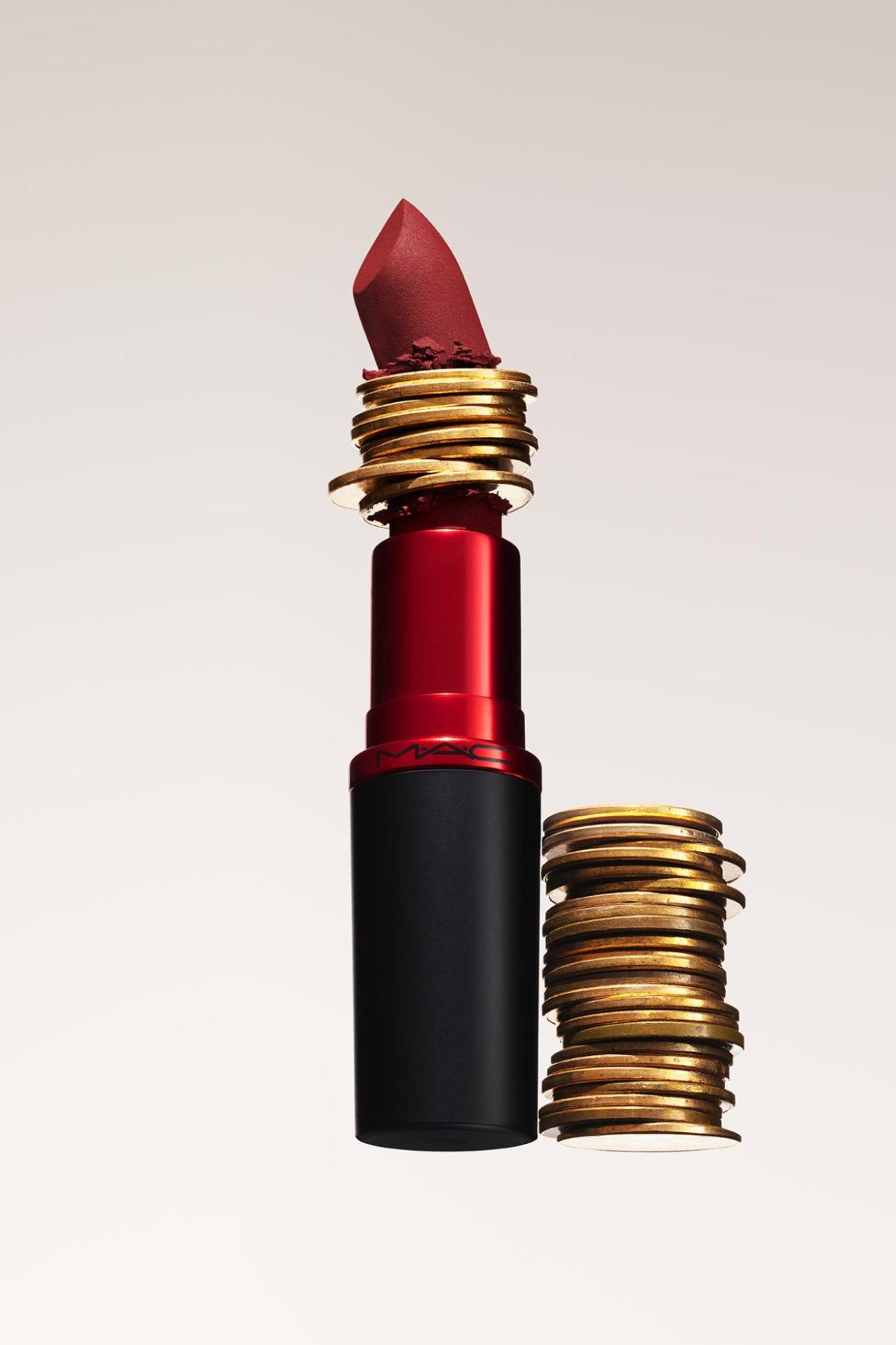 A lipstick with stacked coins in the middle of it and to the side.