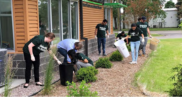 A team of volunteers picking up trash outside a building.