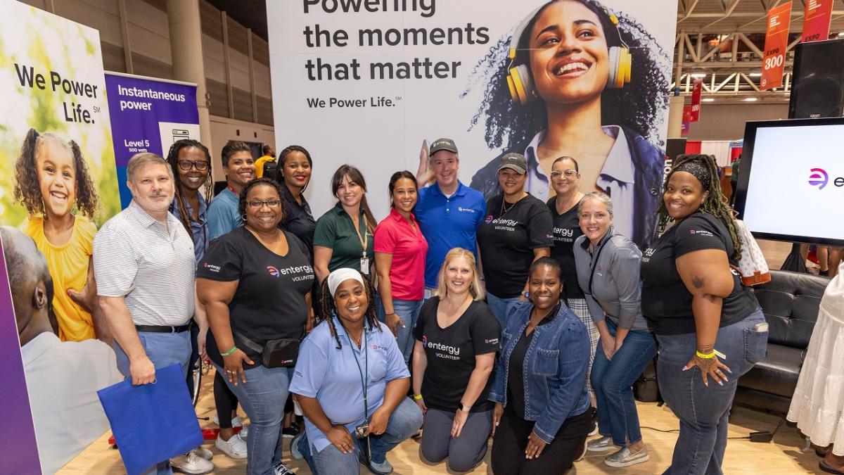 People posed together surrounded by signs "We Power Life" and "Powering Moments That Matter."