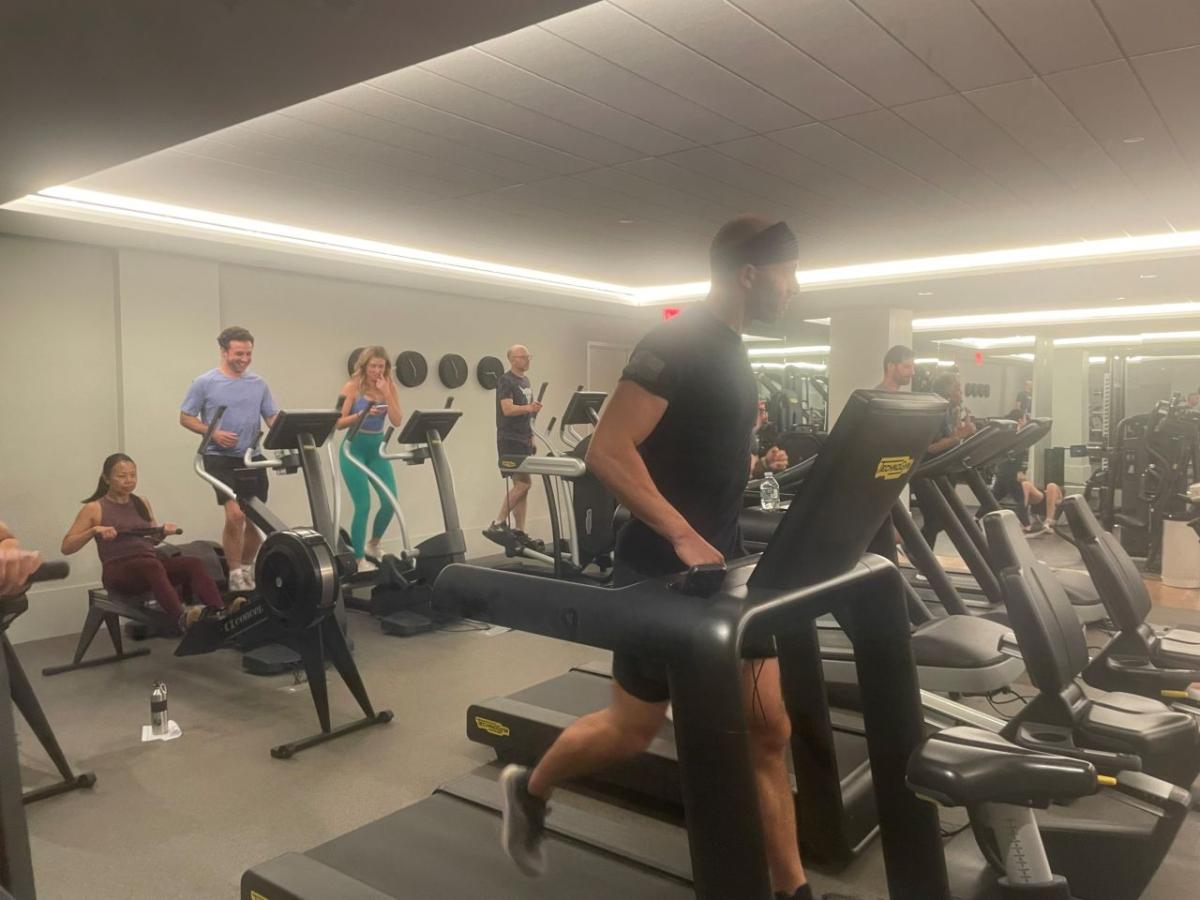 A group of people exercising on different machines in a gym.