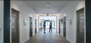 Two people at the end of an office hallway talking with each other.