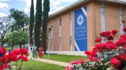 People walking down a sidewalk next to a building "Denmark Technical College" banner on the side.